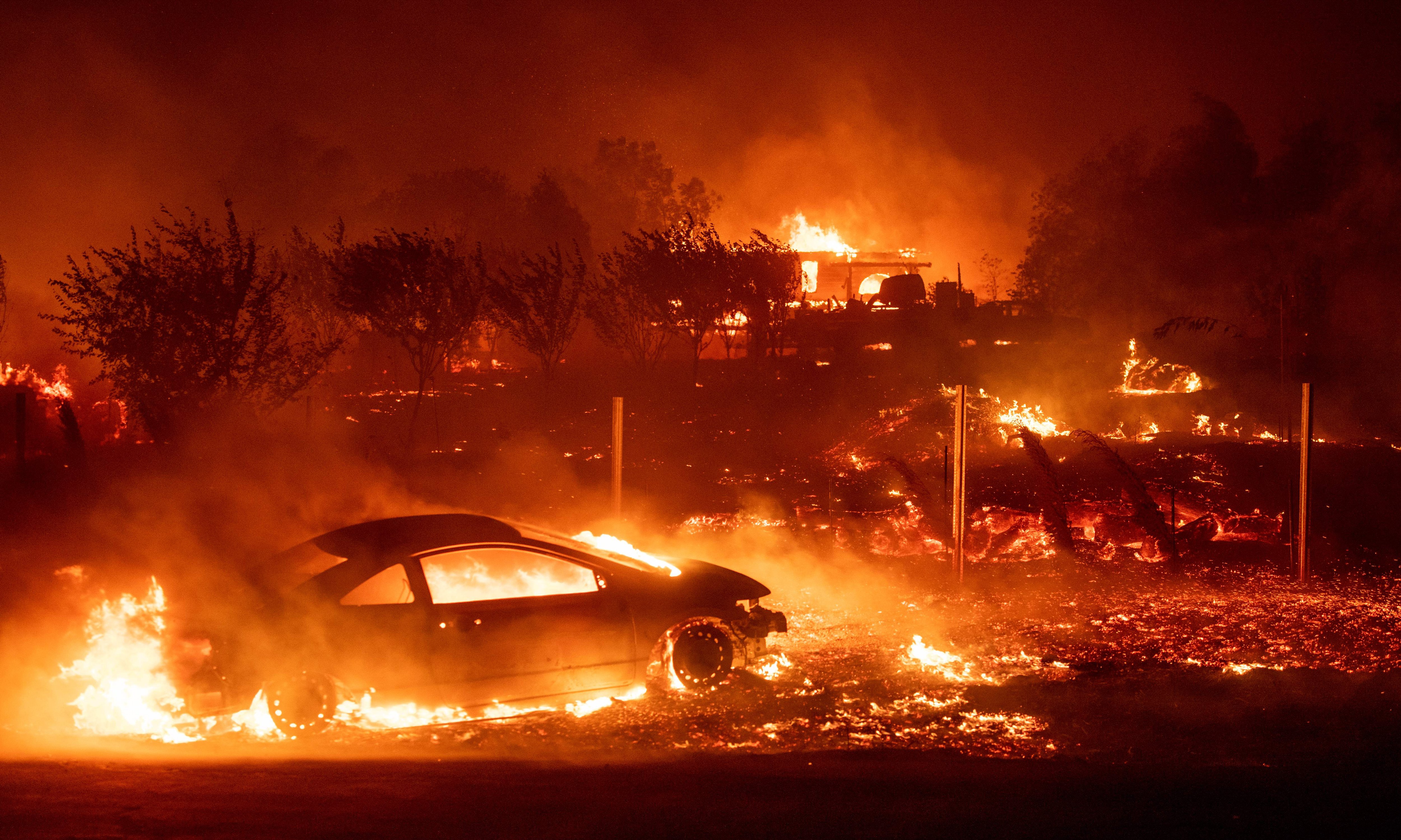 A car and a home burning in a wildfire