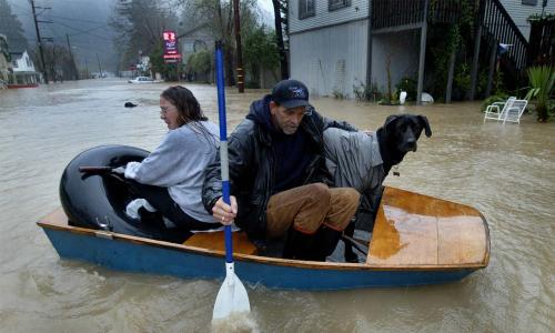 man woman dog rafting in flood waters caused by high flows on California’s Russian River 
