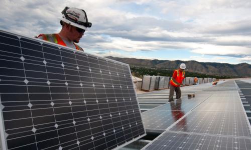 Two workers installing rooftop solar panels