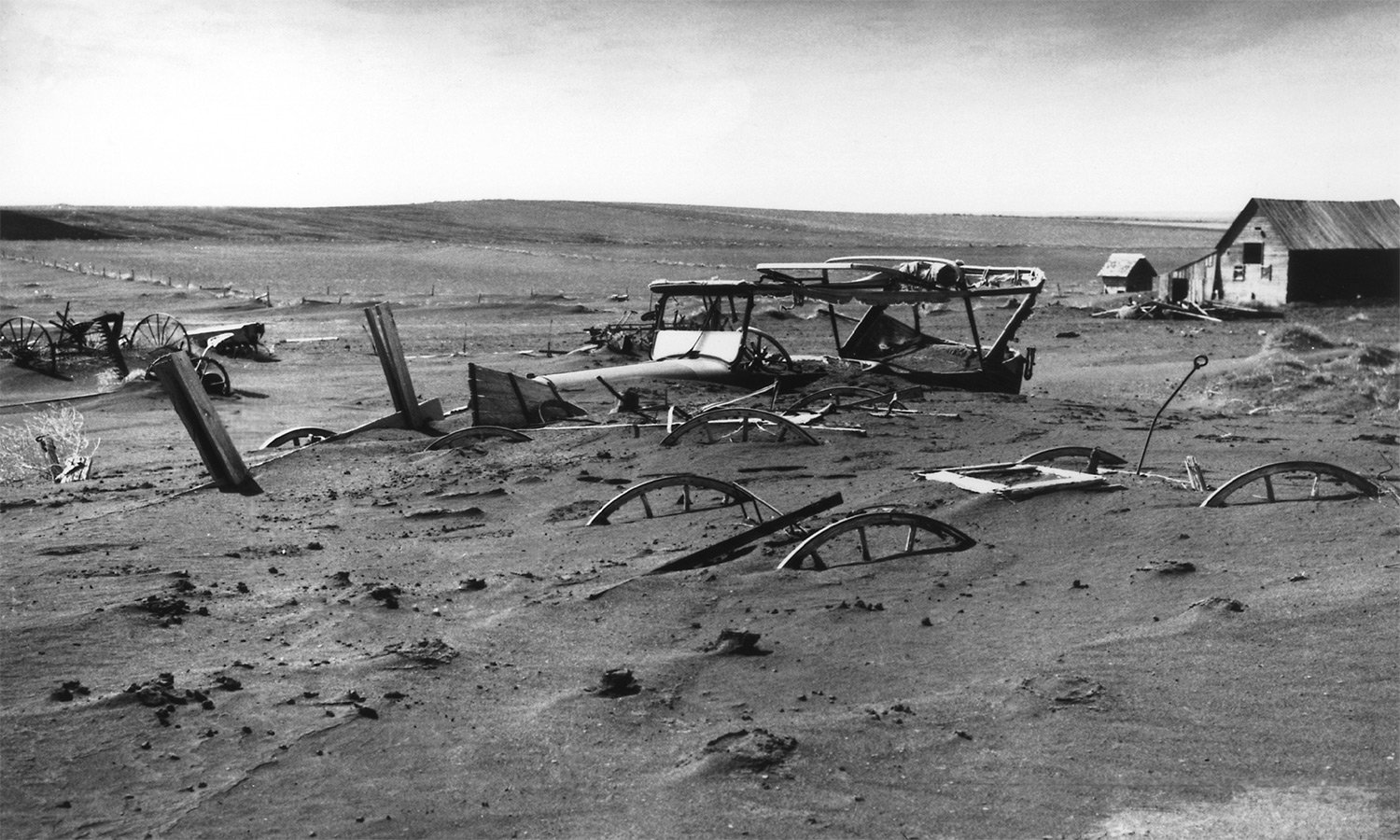 farm equipment buried in eroded soil in the Dust Bowl