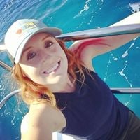 Jess Phoenix is on a boat in clear blue water, wearing a baseball hat