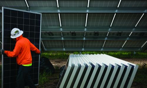 A worker carries a solar panel