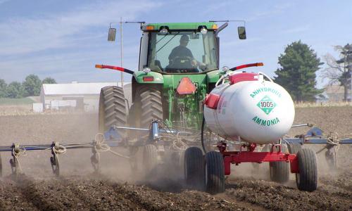 Tractor spraying anhydrous ammonia on crop field