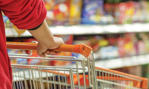 Person pushing shopping cart down snack aisle