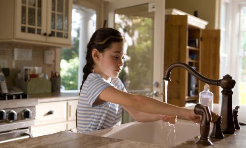 A child using a sink faucet.