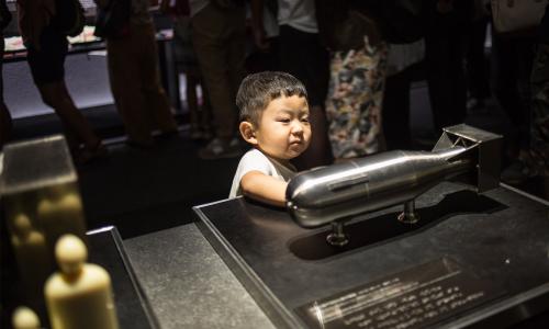 Boy looking at model of atomic bomb model, "little boy" used in WWII