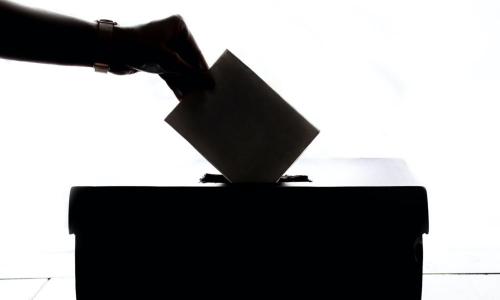 A hand casting a ballot