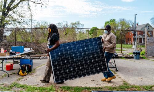 Two people carrying solar panel