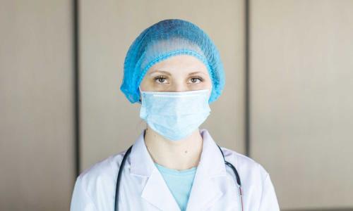A doctor wearing a face mask and hair net.