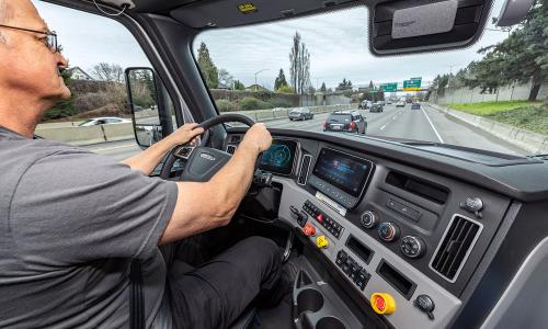 A driver in the cab of a Freightliner eCascadia electric truck